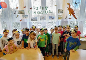 Zdjęcie grupowe – dzieci w opaskach z dinozaurami.